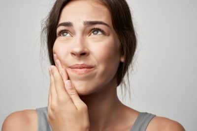 woman holding her jaw due to pain