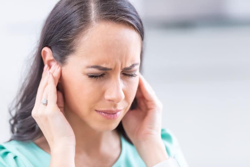 young adult woman holding her ears in pain
